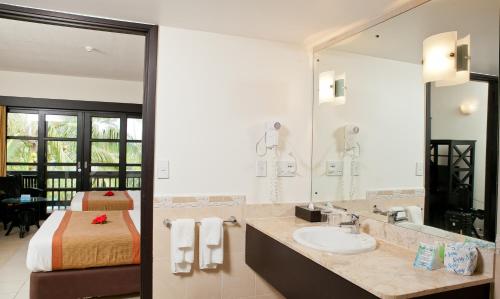 baño con lavabo, cama y espejo en The Naviti Resort, en Korolevu