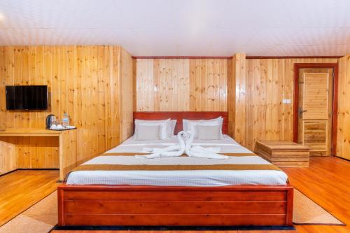 a bedroom with a large bed with wooden walls at 3 Arch Resort Ella in Ella