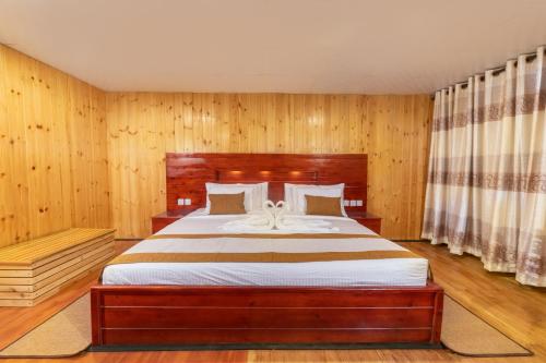 a bedroom with a large bed with wooden walls at 3 Arch Resort Ella in Ella