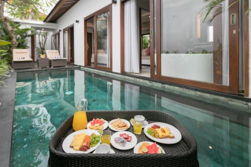 a tray of food on a table next to a swimming pool at Anari Villas Kuta in Legian