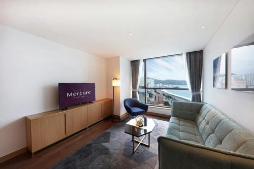 a living room with a couch and a tv at Mercure Ambassador Ulsan in Ulsan