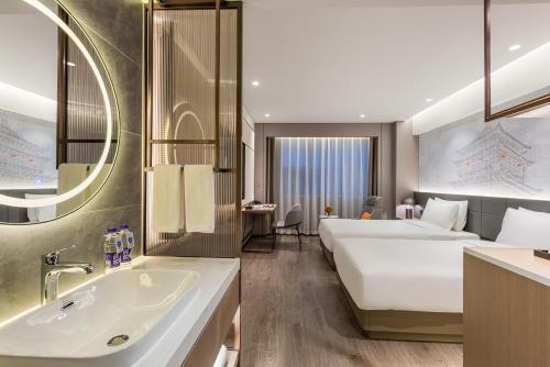 a hotel room with two beds and a sink at Novotel Xi'an The Bell Tower in Xi'an