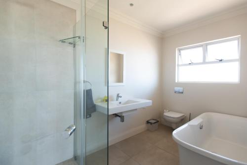 a bathroom with a shower and a sink and a toilet at Howela Beach House in Ballito