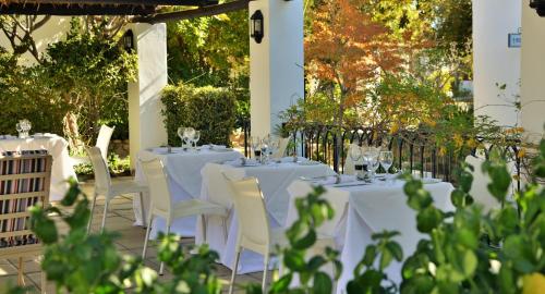 a table with white chairs and wine glasses on it at Mont d'Or Swartberg Hotel in Prince Albert