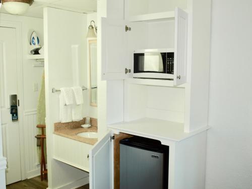 a white kitchen with a microwave and a sink at Atlantic View Hotel in Dewey Beach