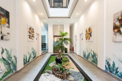 a hallway with plants and paintings on the walls at RedDoorz Premium near Centre Point Mall Medan in Medan