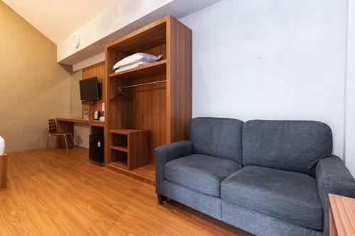 a living room with a blue couch and a desk at RedDoorz Premium near Centre Point Mall Medan in Medan