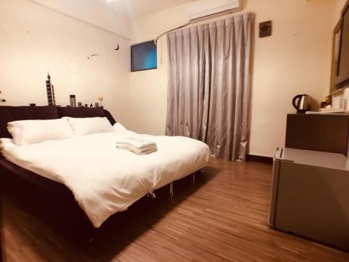 a bedroom with a bed with white sheets and a window at Love Feng Jia Apartment Hotel in Taichung
