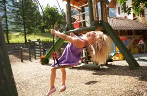 a little girl is playing on a playground at Hotel Des Alpes in Kandersteg