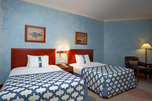 two beds in a hotel room with blue walls at Holiday Inn Al Khobar by IHG in Al Khobar