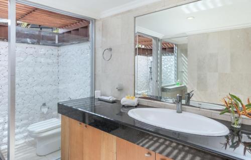a bathroom with a sink and a toilet and a mirror at Villa Hening Jimbaran in Jimbaran