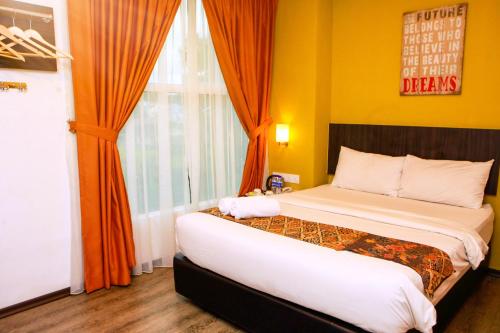 a bedroom with a bed with orange walls and a window at Potpourri Boutique Hotel in Johor Bahru