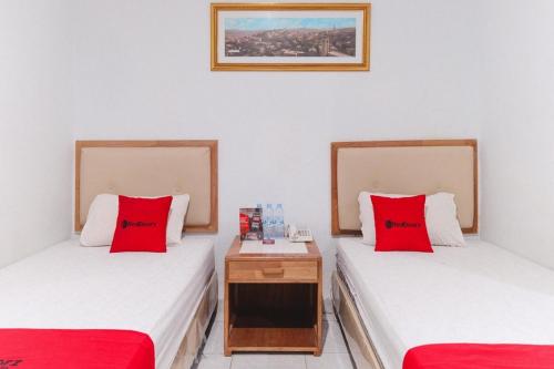 two beds with red pillows in a room at RedDoorz @ Jalan Mojopahit Medan in Medan