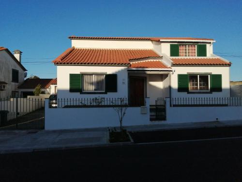 une maison blanche avec des fenêtres vertes et une clôture dans l'établissement Pedro Sousa Rooms na Relva, à Ponta Delgada