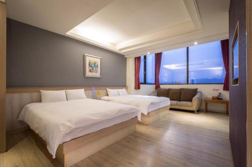 a hotel room with two beds and a couch at Yadi Hotel in Puli