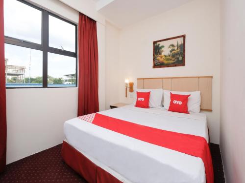 OYO 89968 Sri Sutra Hotel في بيتالينغ جايا: غرفة فندق بسرير كبير ومخدات حمراء