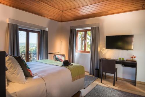 a bedroom with a bed and a desk and a television at Quinta das Pedras in Sintra