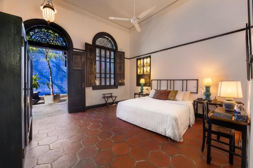 a bedroom with a bed and a desk and windows at Cheong Fatt Tze - The Blue Mansion in George Town