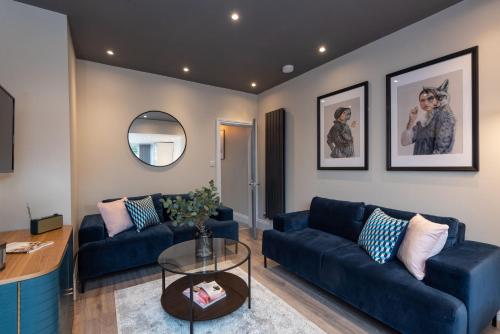 a living room with blue couches and a mirror at Cherry Orchard in Shrewsbury