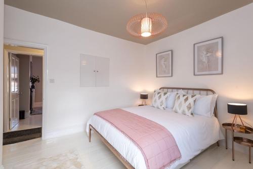 ein weißes Schlafzimmer mit einem Bett mit einer rosa Decke in der Unterkunft Cherry Orchard in Shrewsbury