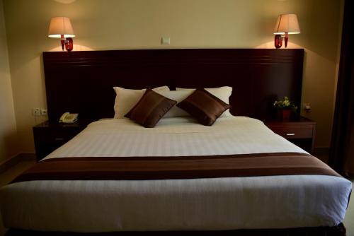 a bedroom with a large bed with two lamps at Nobleza Hotel in Kigali
