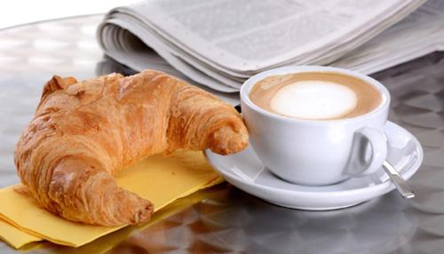 uma chávena de café e um croissant numa mesa em B&B Sant'Agostino em Milão