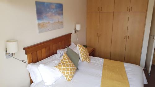 Schlafzimmer mit einem Bett mit weißer Bettwäsche und Kissen in der Unterkunft Moonlight @ Port Marina in Velddrif