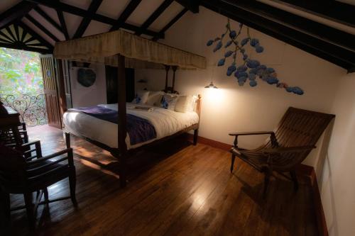 a bedroom with a canopy bed and two chairs at Bate Papo House Cafe Boutique in Saligao