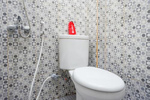 a bathroom with a white toilet with a red bottle on it at Gosyen Efata Toraja Hotel in Makale