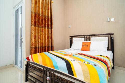 a bedroom with a bed with a colorful blanket at Sitiinggil Syariah RedPartner in Tegal