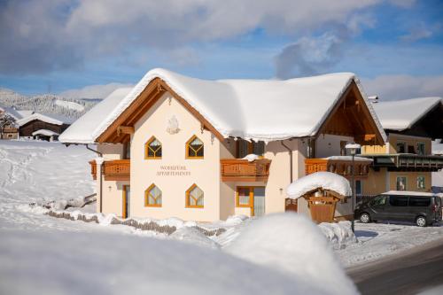 a house covered in snow with a car parked in front at Flachauer Bergkristall in Flachau