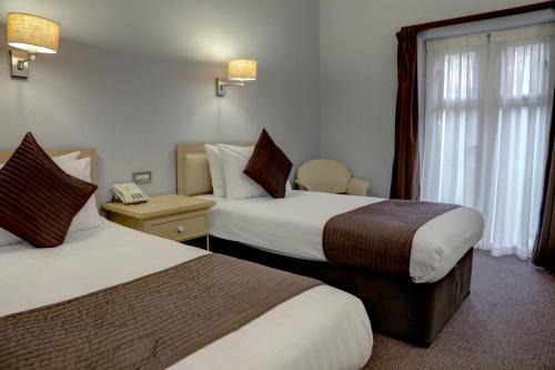 a hotel room with two beds and a telephone at The Regency Hotel in Solihull