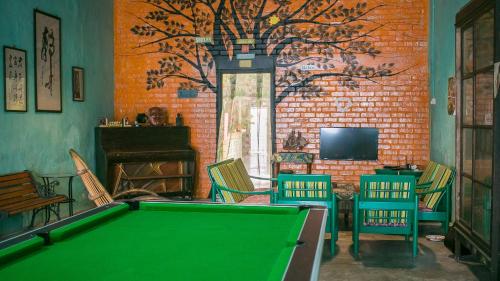 a pool table in a room with a tree mural at Voyage Home&Guesthouse in Melaka