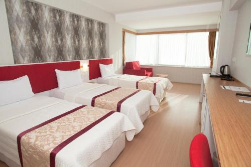 a hotel room with three beds and a desk at Samsun Konaks in Samsun