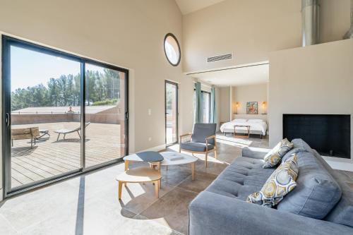 een woonkamer met een blauwe bank en een groot raam bij Loft d'architecte au coeur d'un domaine viticole in La Cadière-dʼAzur