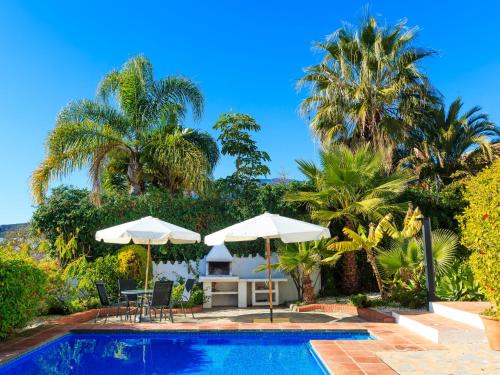 een zwembad met parasols en een tafel en stoelen bij Villa Las Granadillas by Interhome in Estepona