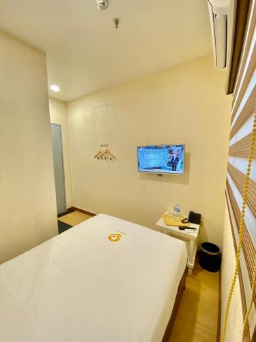 a small room with a bed and a tv at SUN MY HOTEL in Davao City