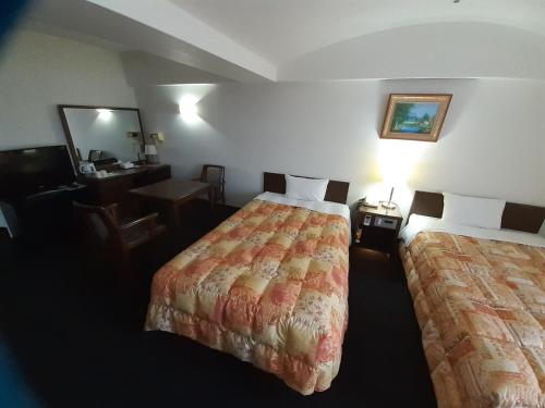 a hotel room with two beds and a desk at Hotel New Plaza Kurume in Kurume