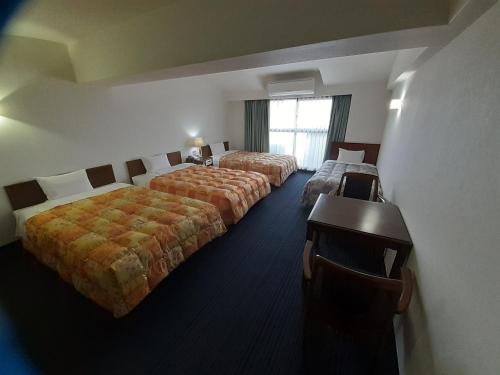a hotel room with two beds and a window at Hotel New Plaza Kurume in Kurume