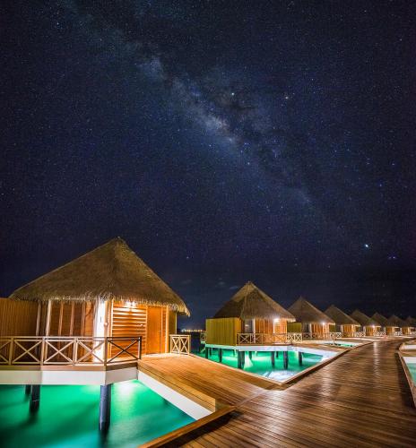 a row of huts at night with the milky way at Mercure Maldives Kooddoo - Adults - Only Escape - 50 percent off Transfers in Gaafu Alifu Atoll