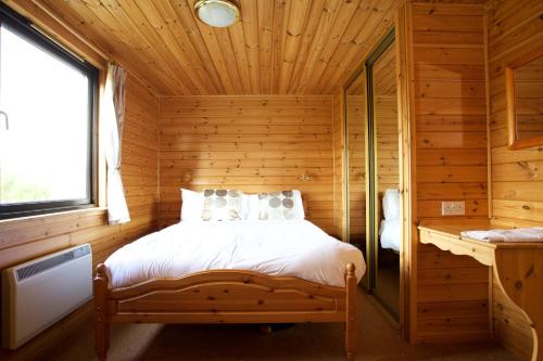 1 dormitorio con 1 cama en una cabaña de madera en Concraig Lodge, en Crieff