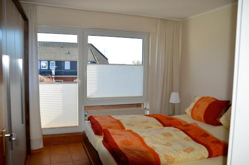 een slaapkamer met een bed en 2 grote ramen bij Ferienwohnung Besslich Wattweg 5 in Norden