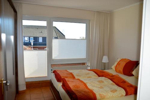a bedroom with a bed and two large windows at Ferienwohnung Besslich Wattweg 5 in Norden