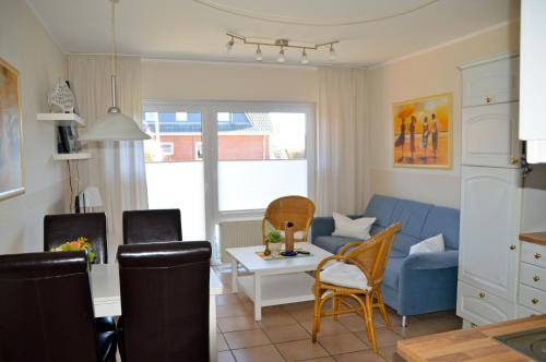 een woonkamer met een blauwe bank en een tafel bij Ferienwohnung Besslich Wattweg 5 in Norden