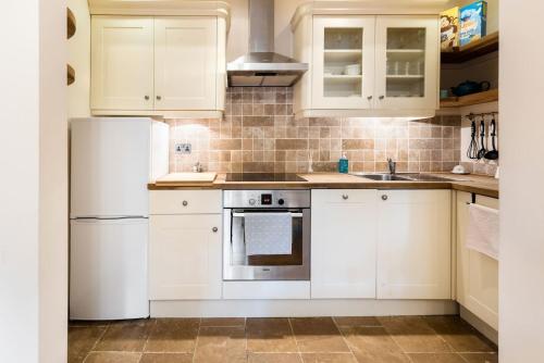 a kitchen with white cabinets and a white refrigerator at Bikki Apartments - 2 Bedroom in Harrow