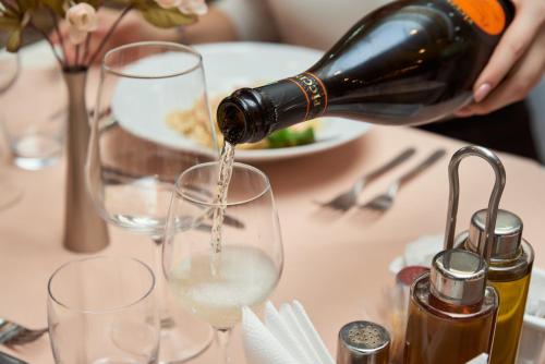 a person pouring wine into a wine glass on a table at Hotel Pushkin in Uralsk