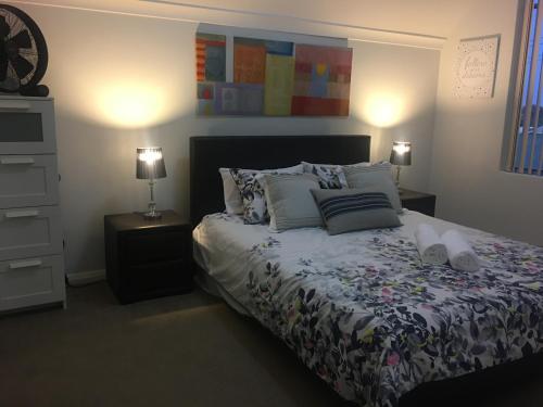 um quarto com uma cama com almofadas e 2 candeeiros em Villa Serenity On The Terrace em Mandurah