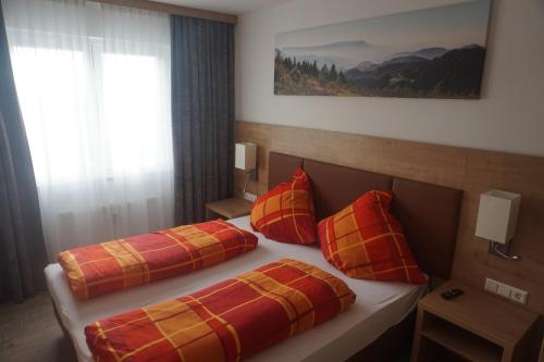 1 Schlafzimmer mit 2 Betten mit roten und orangefarbenen Kissen in der Unterkunft Ferienwohnung Gipfelstürmer Feldberg - Ski in Ski out, Whirlpool & Infrarotkabine in Feldberg