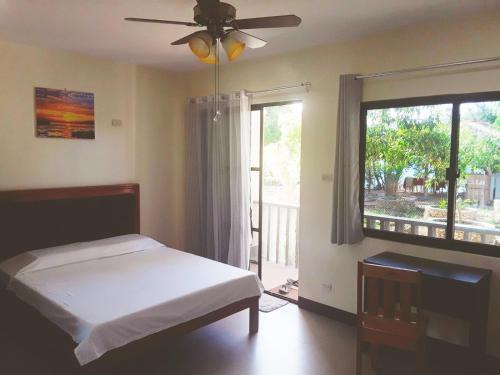 a bedroom with a bed with a ceiling fan and a window at Adayo Cove Resort in Siquijor