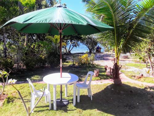 a table and two chairs under a green umbrella at Adayo Cove Resort in Siquijor